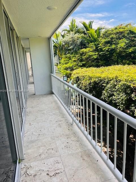 Covered balcony featuring stone flooring, a white metal railing, and recessed ceiling lighting