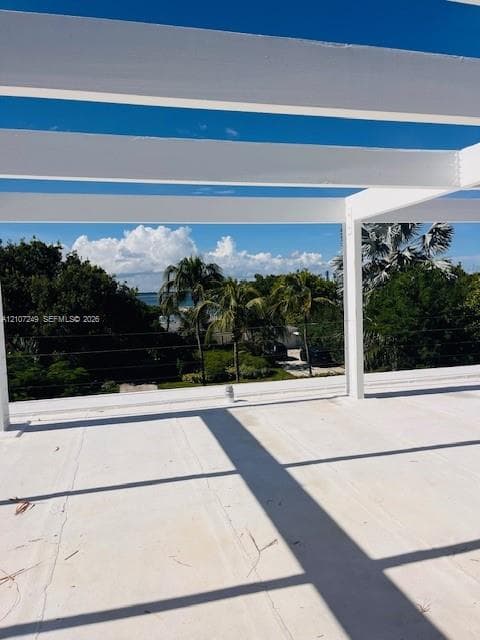Open-air terrace featuring a white pergola structure, smooth concrete surface, and integrated cable railing