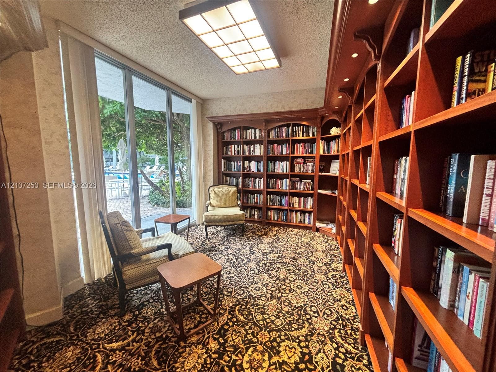 Extensive floor-to-ceiling custom wood shelving with integrated lighting, expansive window wall, and recessed grid ceiling panel