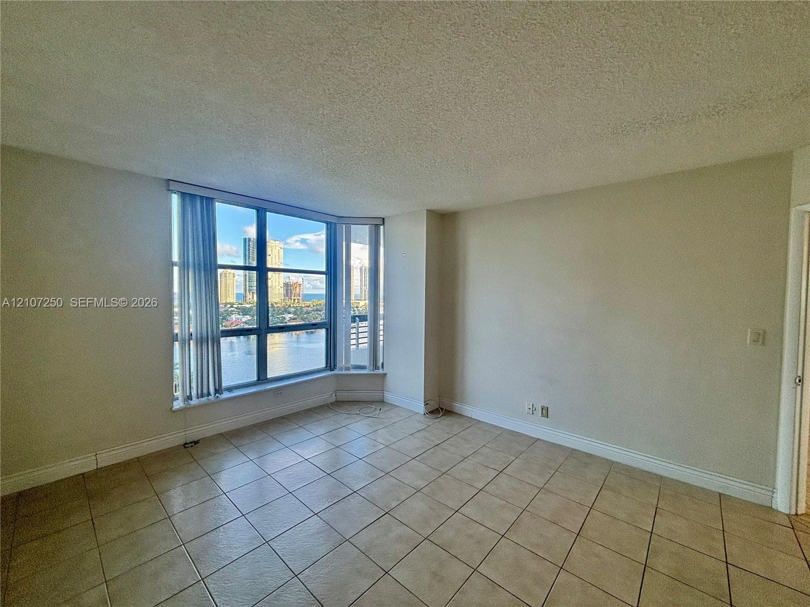Living area featuring oversized bay windows, ceramic tile flooring, and panoramic waterfront and cityscape scenery