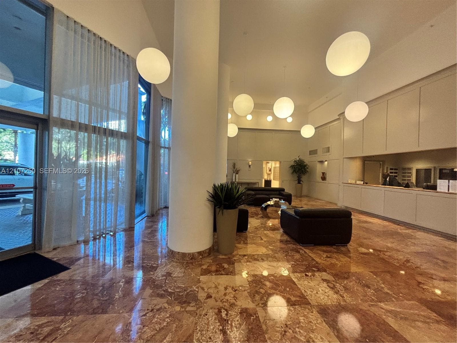 Polished stone flooring, floor-to-ceiling windows, built-in reception cabinetry, and spherical pendant lighting