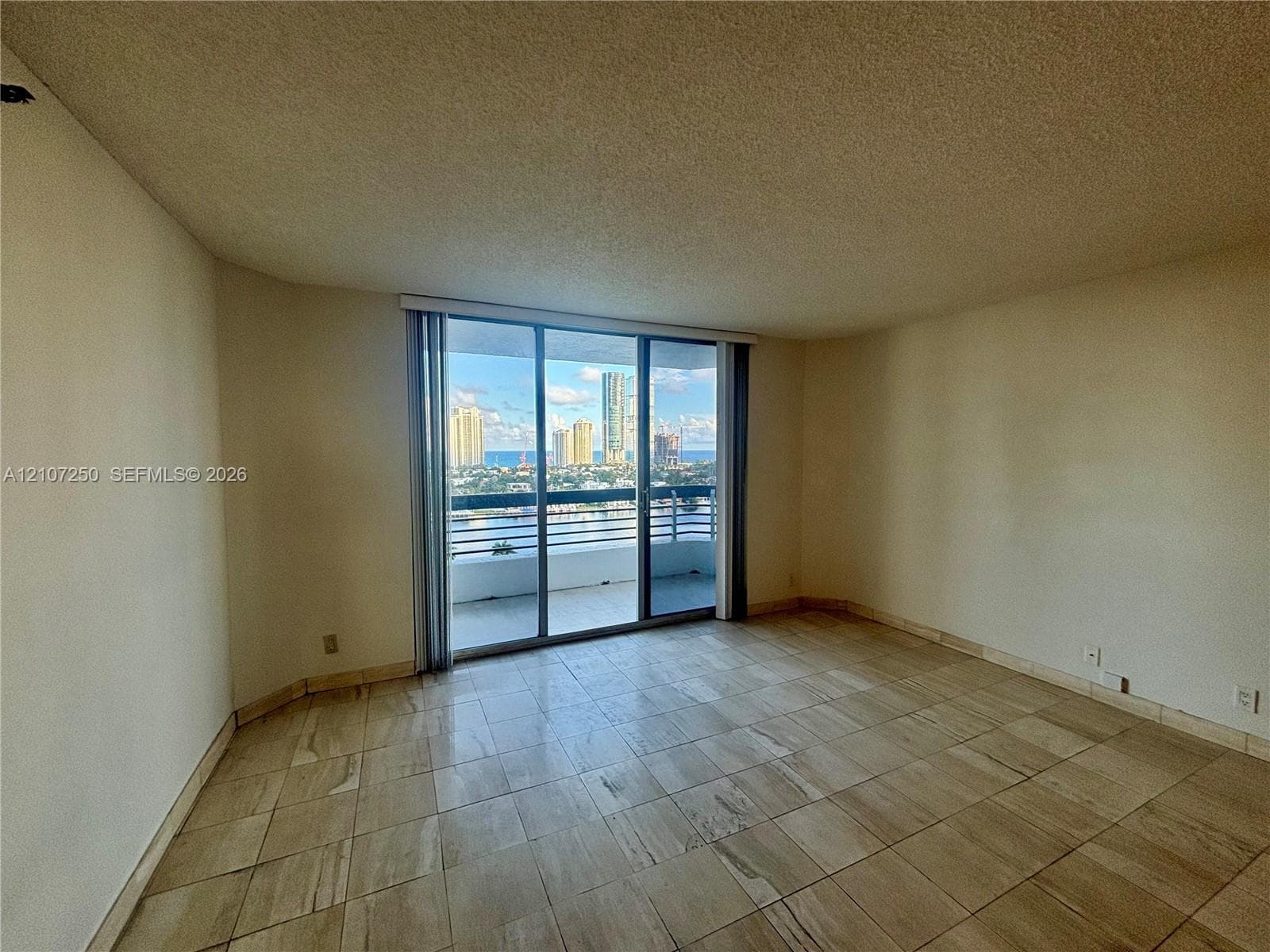 Interior space featuring large-format stone tile flooring and floor-to-ceiling sliding glass doors opening to a private balcony