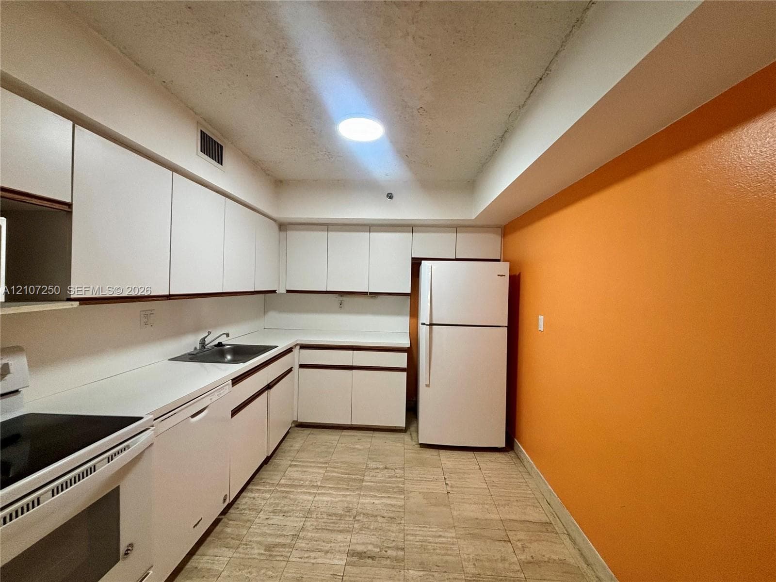 Kitchen featuring white cabinetry, solid-surface countertops, integrated sink, and stone-finish flooring