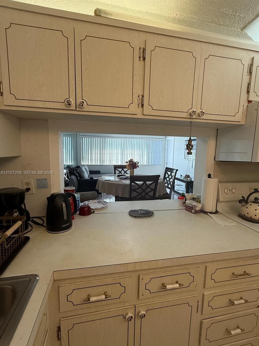 Kitchen featuring raised-panel cabinetry, light-toned countertops, and a pass-through opening