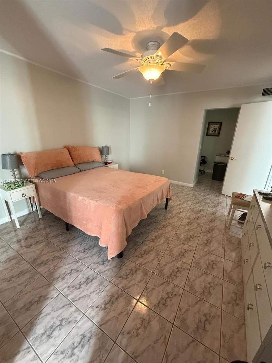 Spacious room featuring neutral wall tones, large-format ceramic tile flooring, and a central ceiling fan with an integrated light fixture