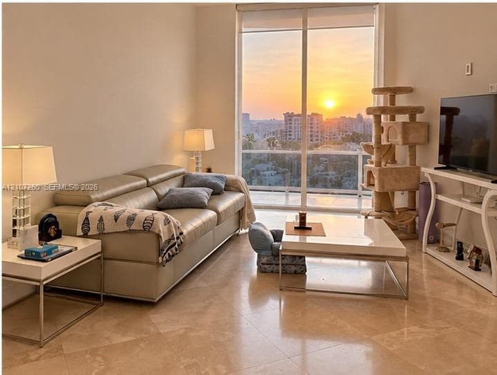 Floor-to-ceiling windows with a sunset cityscape backdrop and stone-finish tile flooring