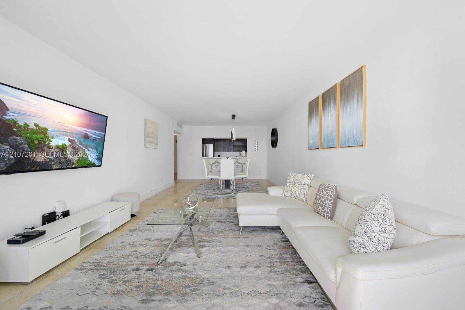 Open-concept interior featuring neutral wall tones, large-format tile flooring, and a kitchen pass-through window