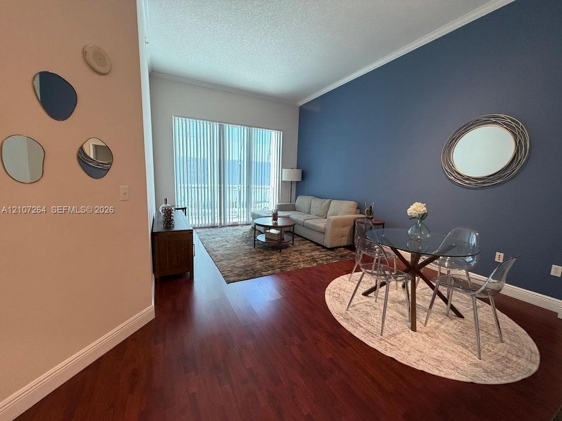 Living area featuring dark wood-finish flooring, vaulted ceilings, and large sliding glass doors with vertical blinds
