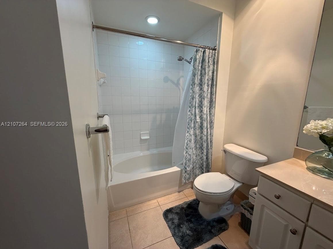 Bathroom featuring an oval soaking tub, tiled tub-to-ceiling surround, recessed lighting, and a neutral-toned vanity with a solid-surface countertop