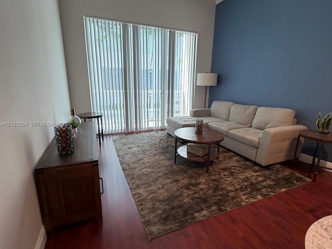 Floor-to-ceiling vertical blinds, wood-finish flooring, and a blue accent wall