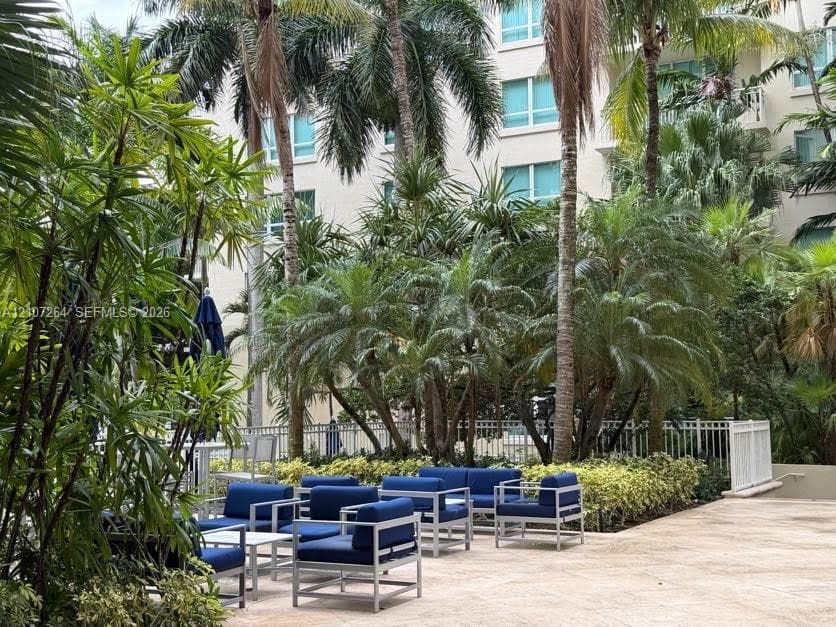 Landscaped courtyard featuring mature palm trees, tropical foliage, and stone-finish paving