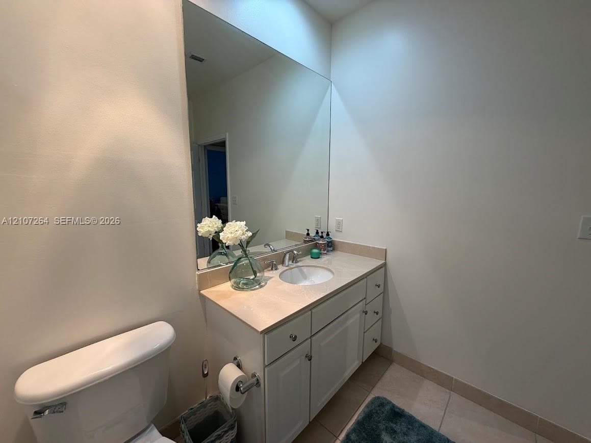 Bathroom featuring a vanity with a stone-surface countertop, an integrated undermount sink, chrome fixtures, and a wall-to-wall mirror