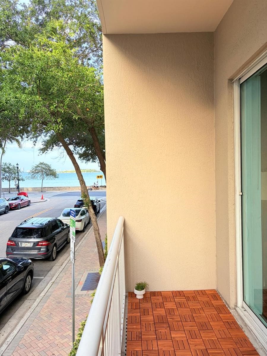 Covered balcony featuring wood-finish deck tiling and a white metal railing