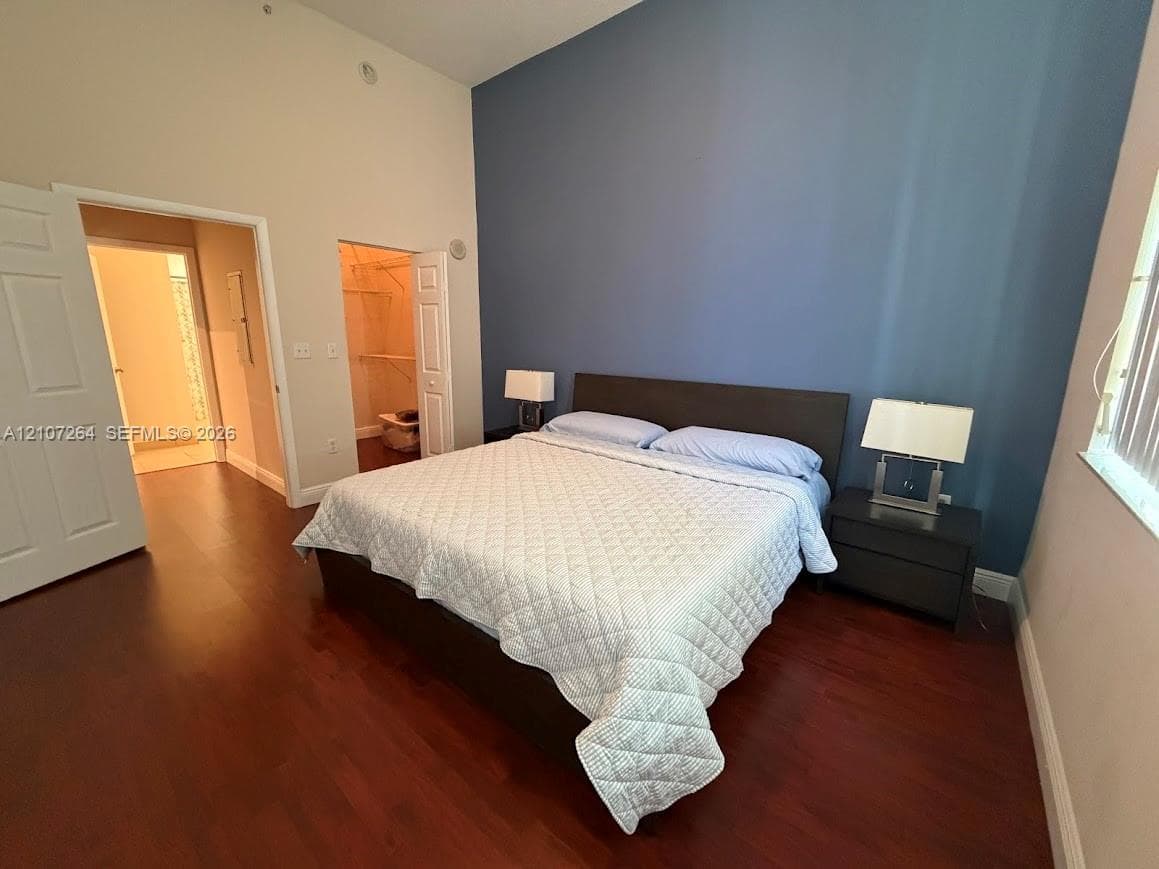 Vaulted ceilings, wood-finish flooring, and a blue accent wall with walk-in closet and panel doors