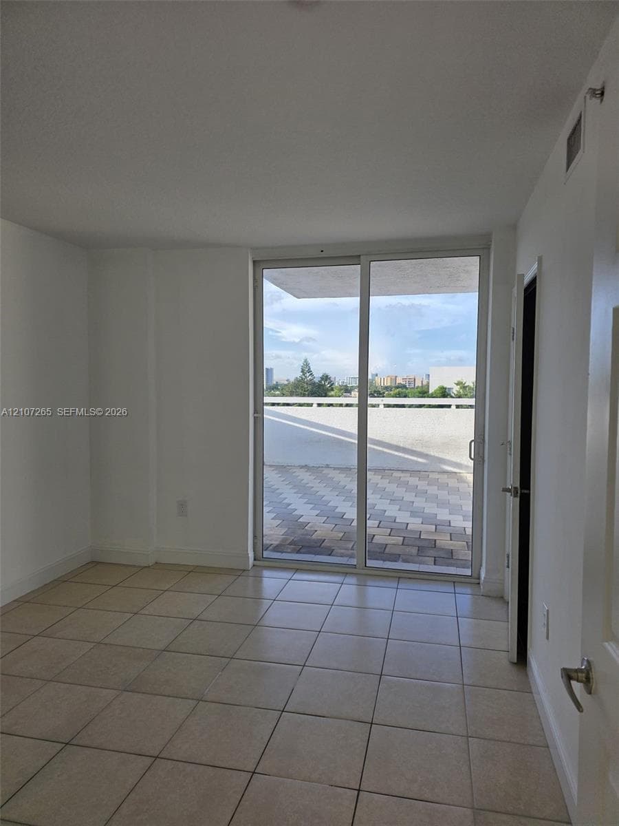 Interior room featuring large-format ceramic tile flooring, sliding glass doors, and a private outdoor terrace with patterned paver stones