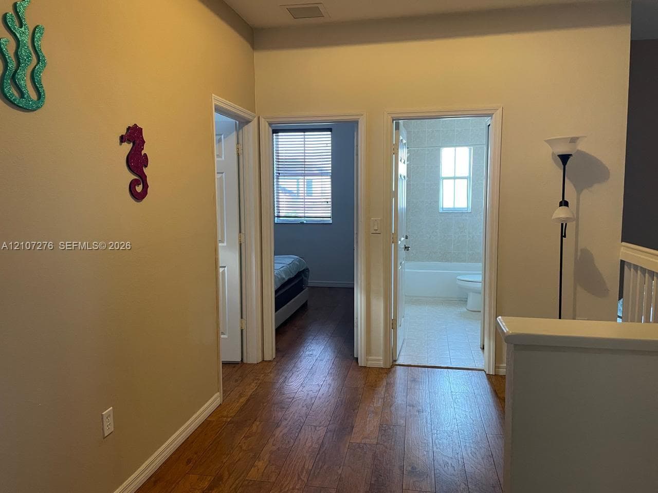 Hallway featuring wood-finish flooring, two paneled interior doors, and a partial height wall with a finished cap