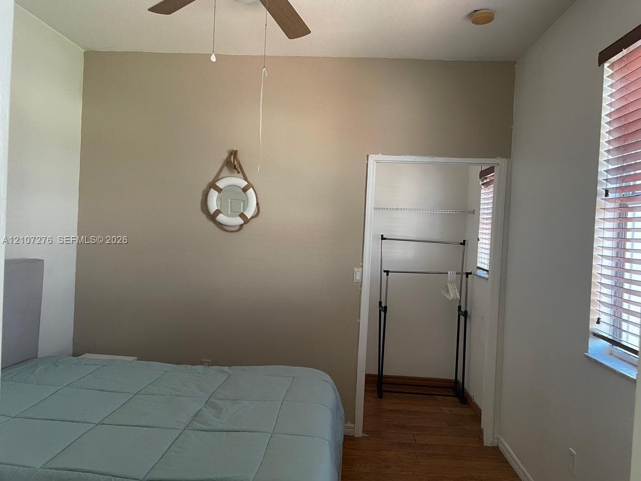 Interior space featuring wood-finish flooring, a ceiling fan with integrated lighting, and a window with horizontal blinds