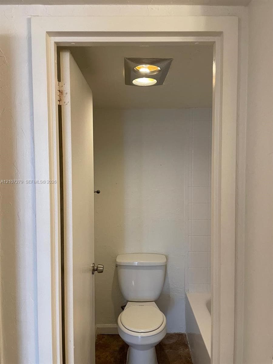 White porcelain commode and recessed ceiling lighting featuring a square-frame fixture