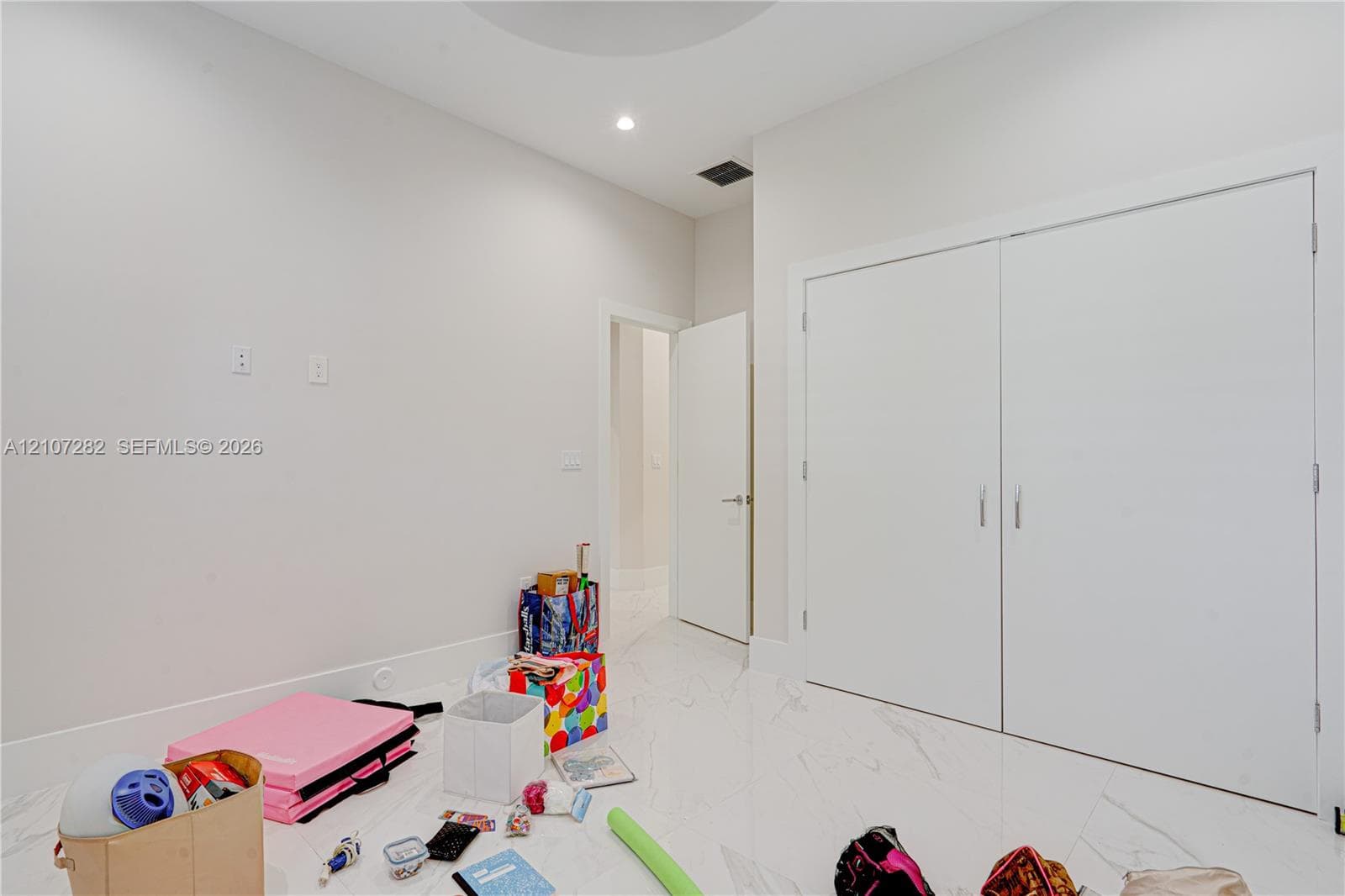 Neutral-toned interior featuring white stone-finish flooring, double-door closet with clean-finish hardware, and recessed ceiling lighting