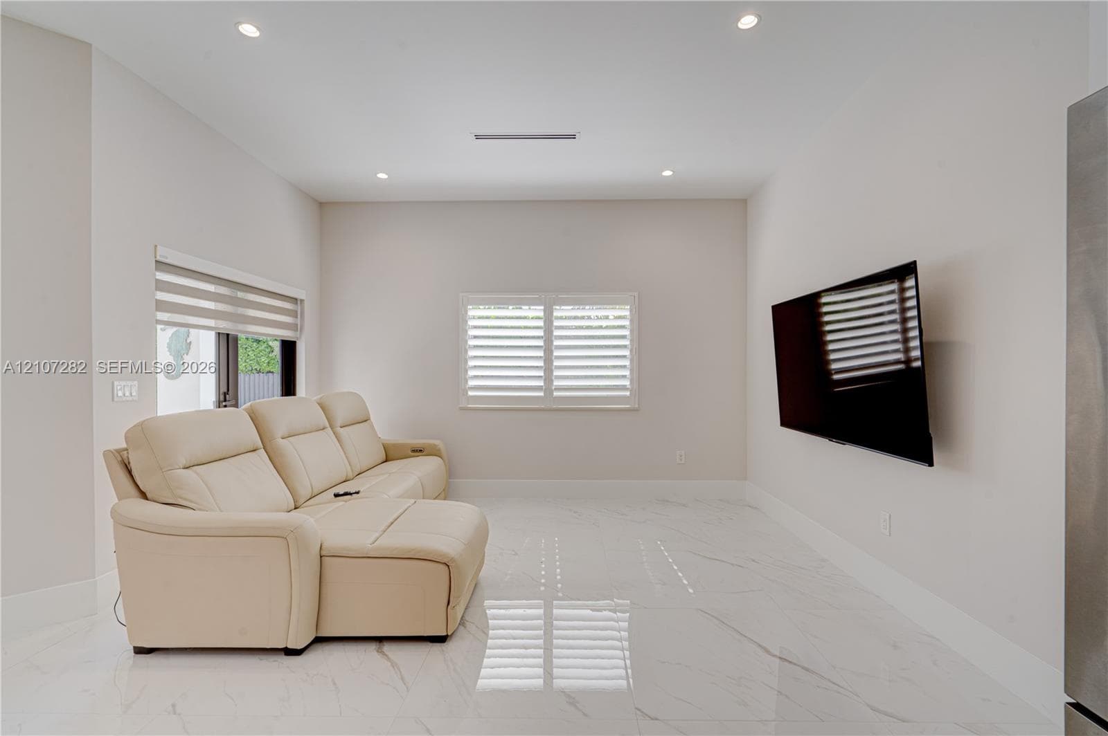 Polished stone-finish flooring, recessed lighting, wall-mounted television, and adjustable window shutters