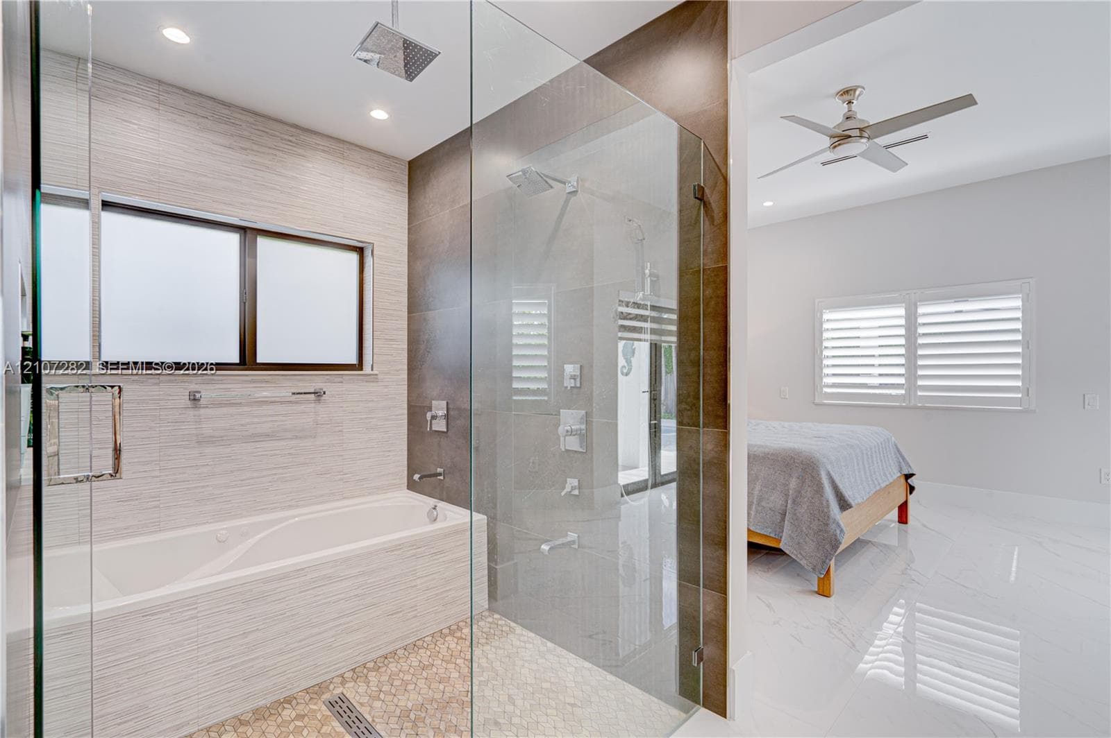 Walk-in glass-enclosed shower featuring a rainfall showerhead and wall-mounted sprayers, built-in soaking tub with textured wall tiling, and large-format polished flooring
