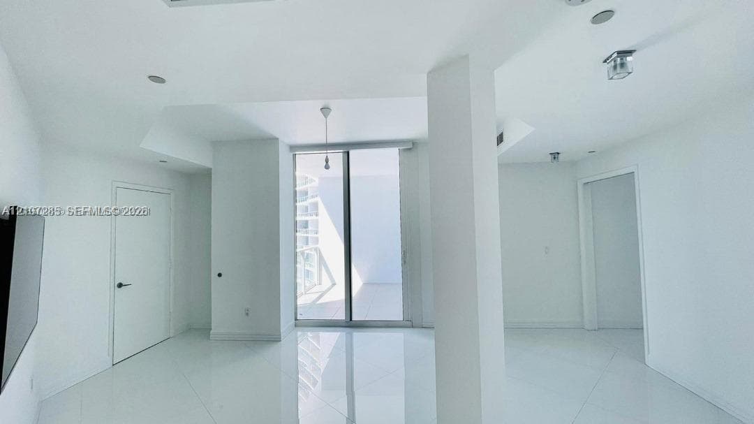 High-gloss floor tiling, ceiling-height glass sliding doors, structural architectural pillar, and recessed ceiling lighting