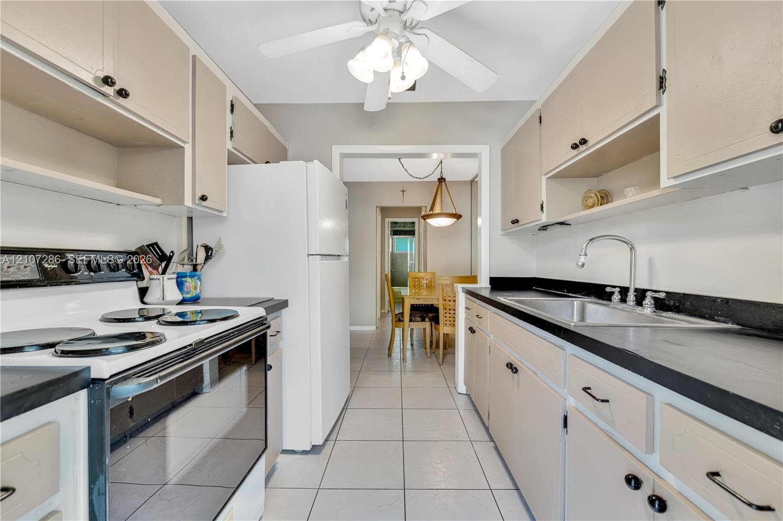 Kitchen featuring flat-panel cabinetry, dark solid-surface countertops, tile flooring, and ceiling-mounted lighting