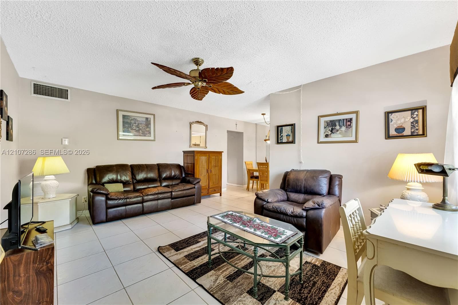 Living space featuring neutral walls, white ceramic tile flooring, and a decorative ceiling fan with leaf-style blades