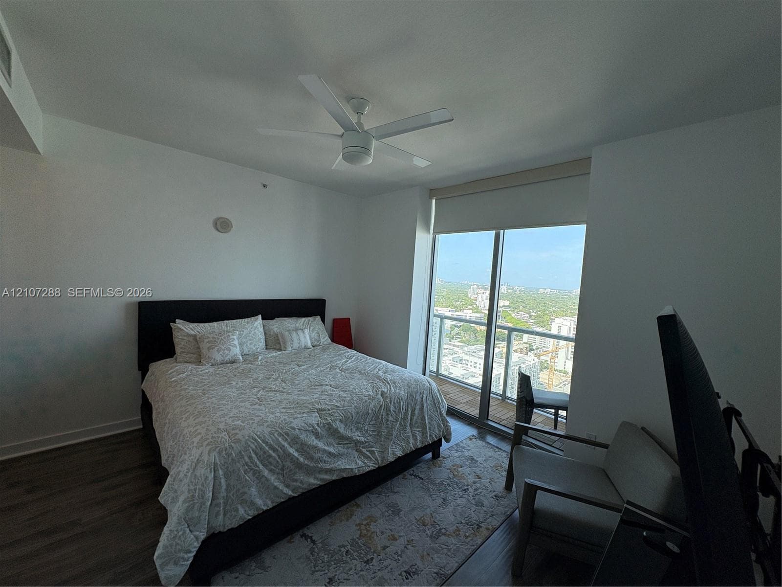 Floor-to-ceiling glass sliding door, expansive balcony, wood-finish flooring, and white ceiling fan