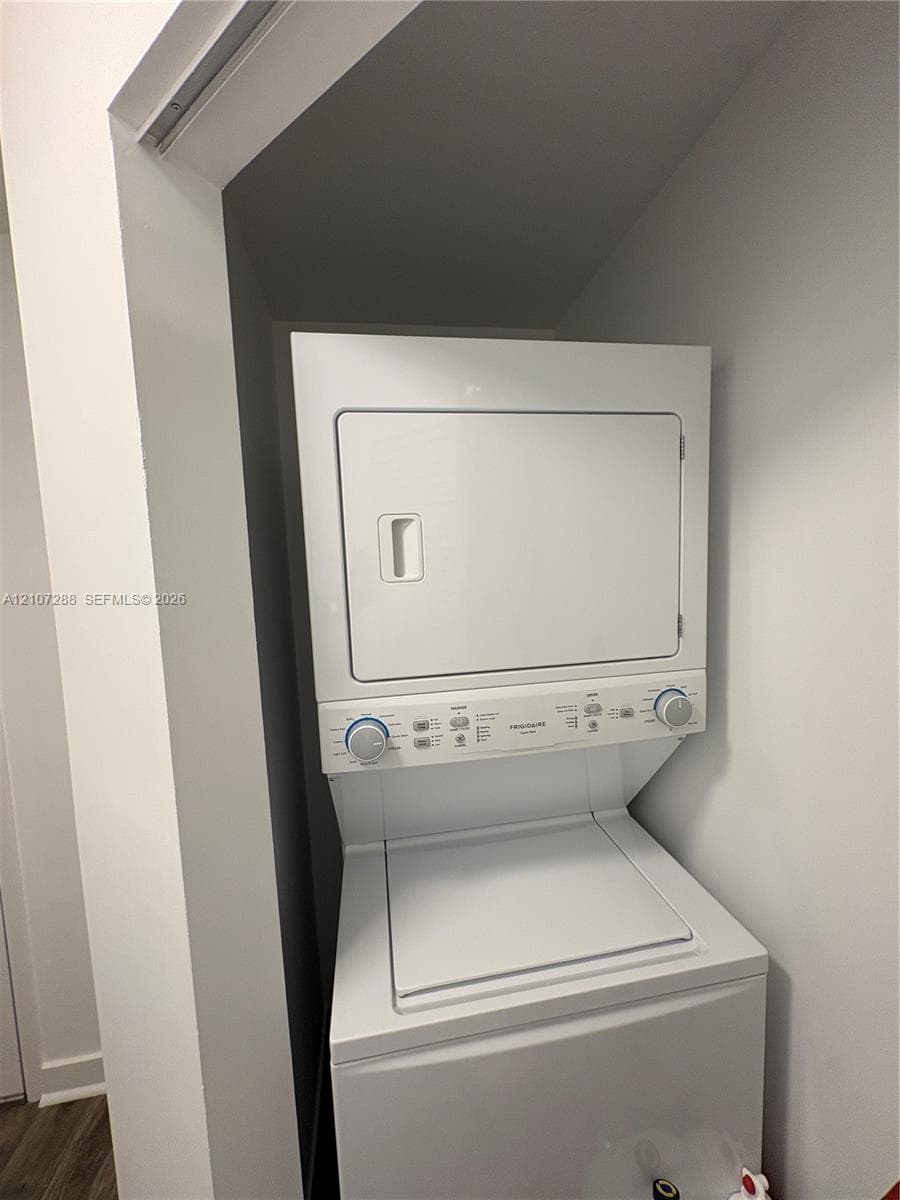 Stackable white laundry unit featuring a top-load washer and front-load dryer in a dedicated recessed closet