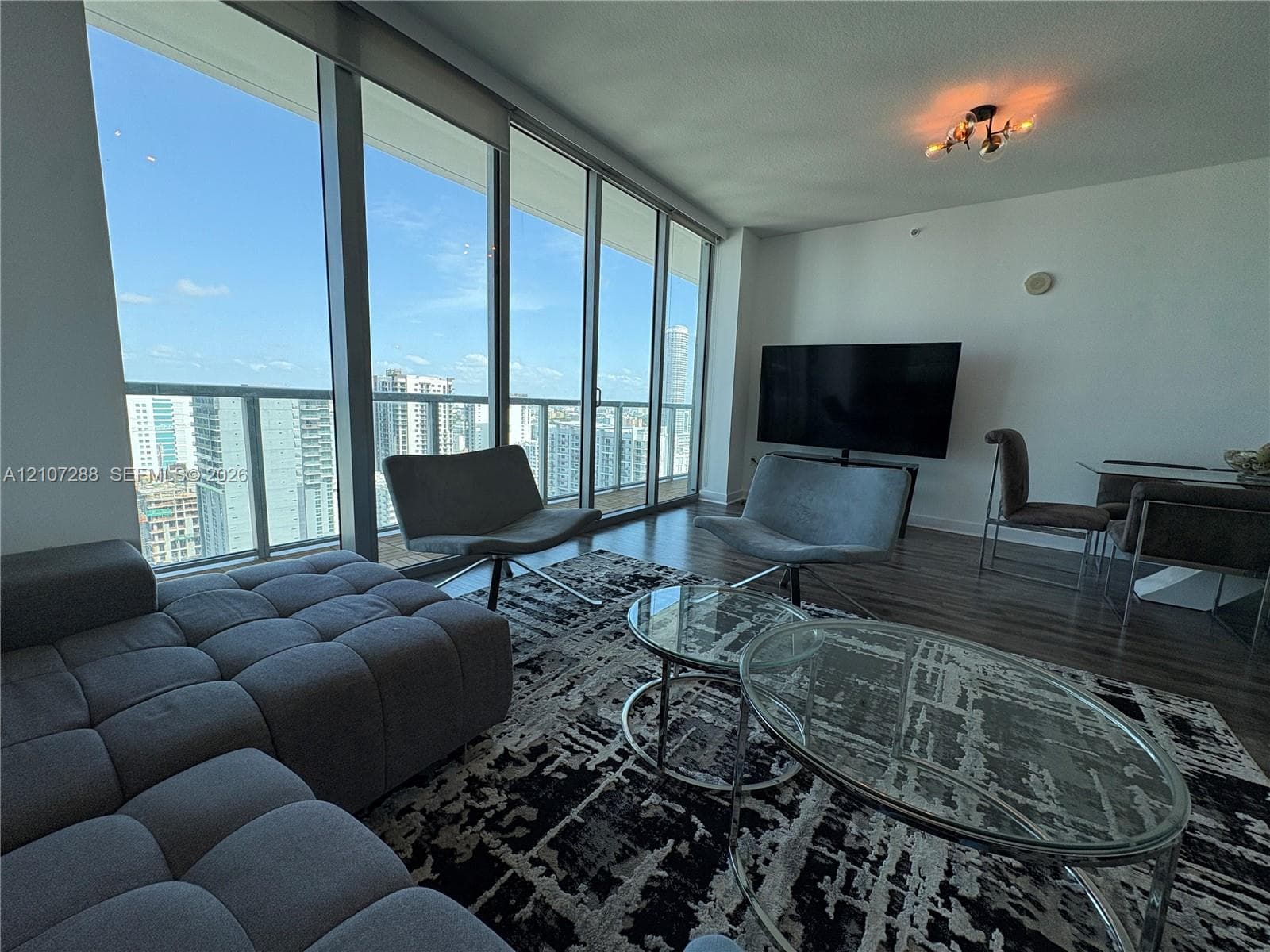 Floor-to-ceiling windows, wood-finish flooring, and access to a balcony with metal railing