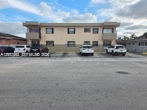 Two-story exterior facade featuring concrete construction, recessed balconies, and dedicated asphalt surface parking