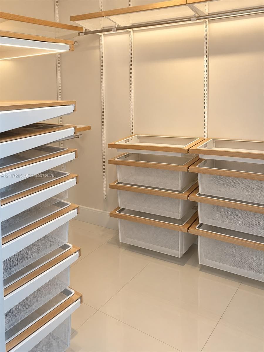 Custom closet system featuring adjustable shelving, integrated wire storage drawers, wood-finish trim, and polished tile flooring