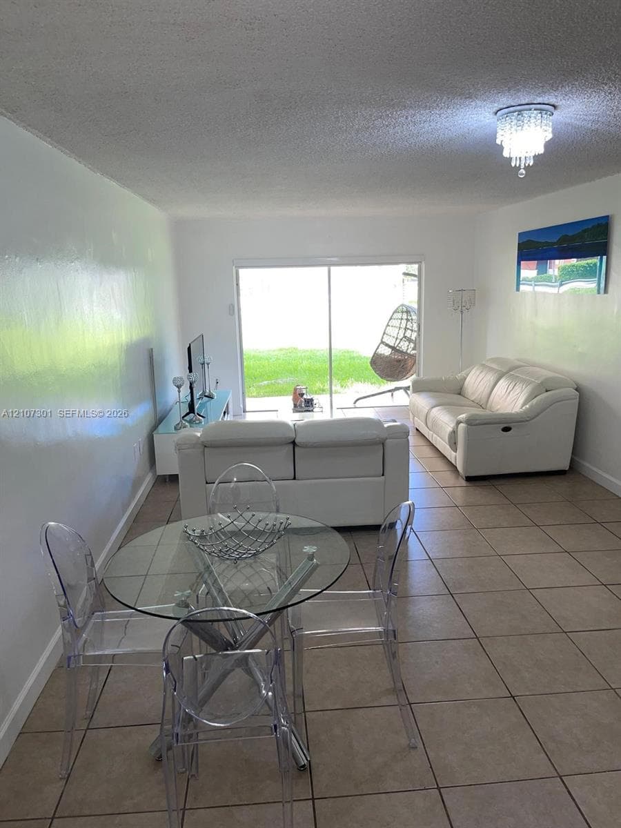 Ceramic tile flooring, crystal-style flush-mount lighting, and large sliding glass doors opening to exterior space