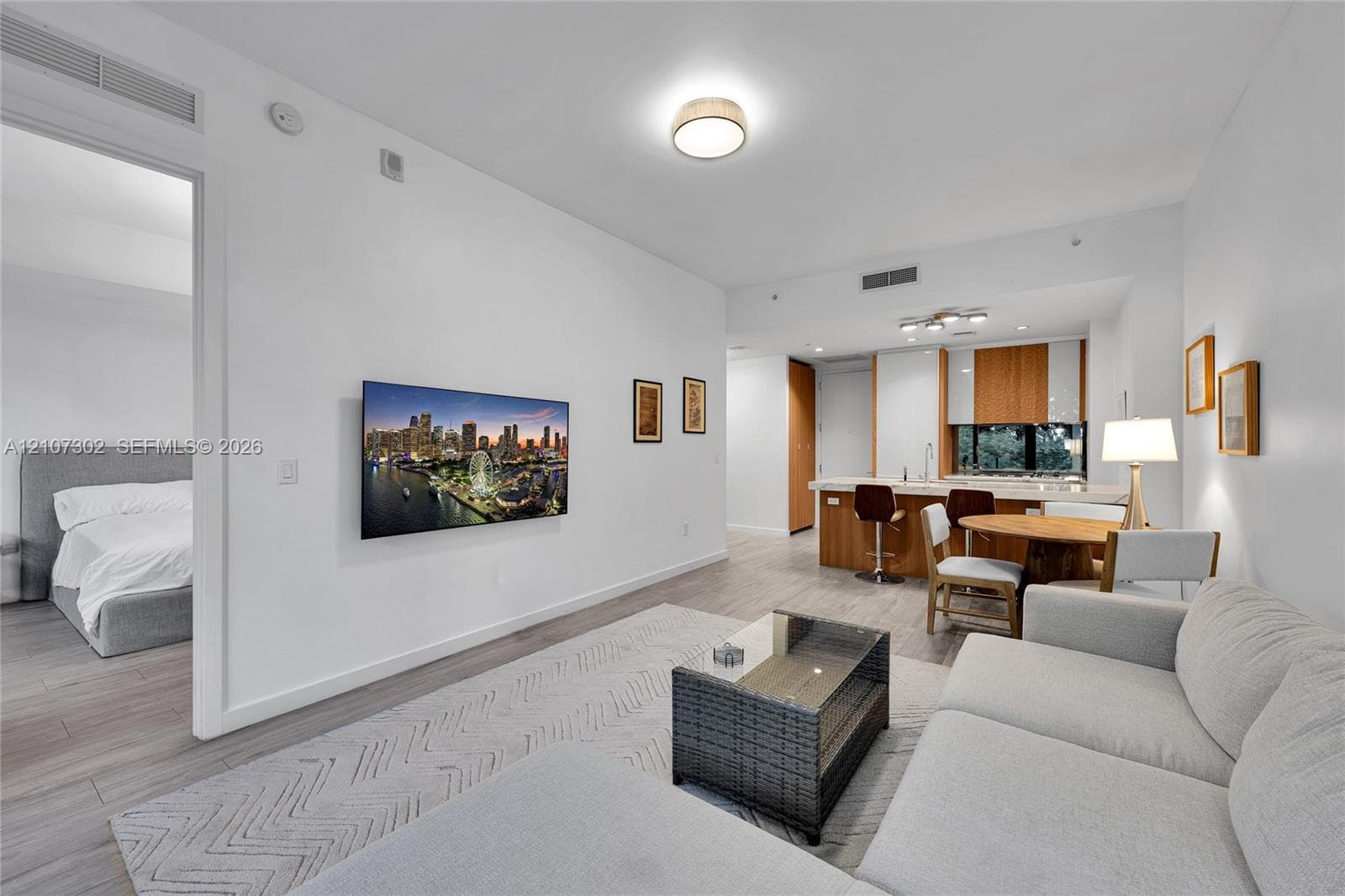 Open-concept living space featuring wood-finish flooring, recessed lighting, and a kitchen island with stone-finish countertops and wood-grain cabinetry