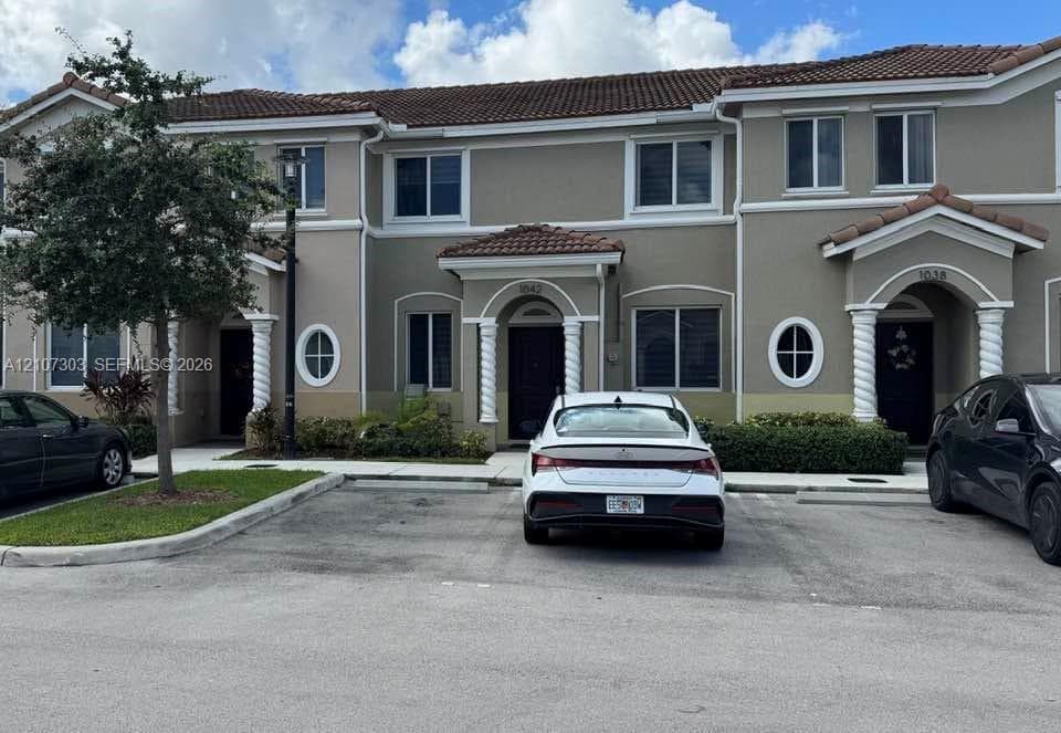 Multi-family exterior featuring a terracotta tile roof, stucco facade, spiral column entryway details, and decorative oval windows