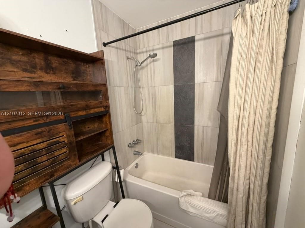 Bathtub with a shower head, encased in floor-to-ceiling ceramic tile with a contrasting vertical accent stripe