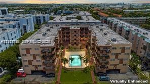 Multi-story residential complex featuring a central courtyard with an outdoor swimming pool, landscaped lawn, and palm trees