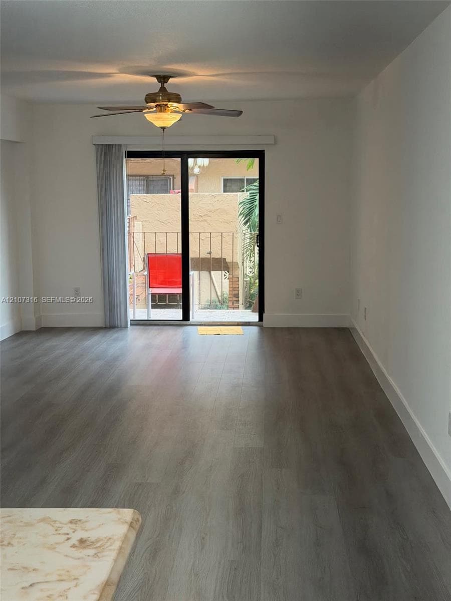 Interior space featuring wood-finish flooring, a ceiling fan with integrated lighting, and a sliding glass door providing external access