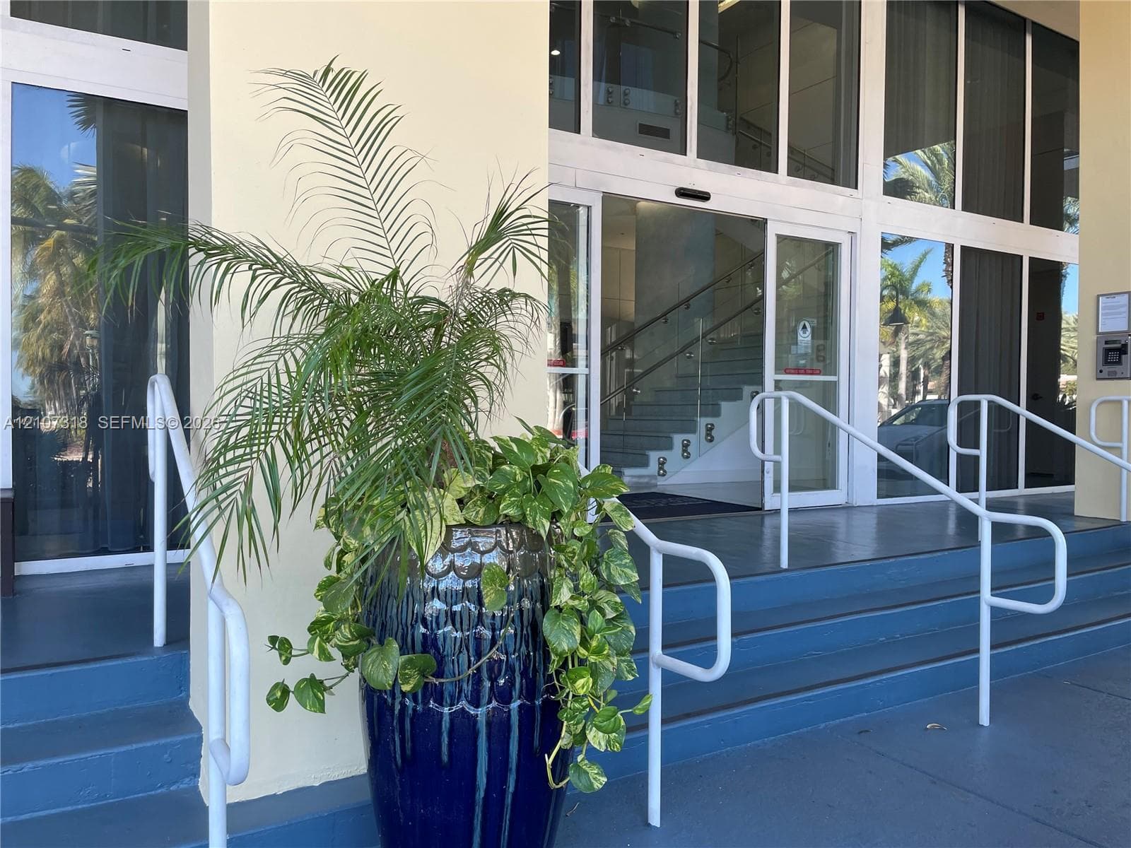 Entryway featuring multi-pane glass doors, floor-to-ceiling windows, white metal handrails, and a painted stair configuration
