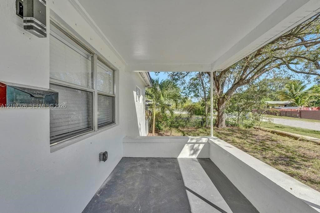 Covered porch featuring concrete flooring, a smooth white ceiling, exterior wall-mounted lighting, and a metal mailbox