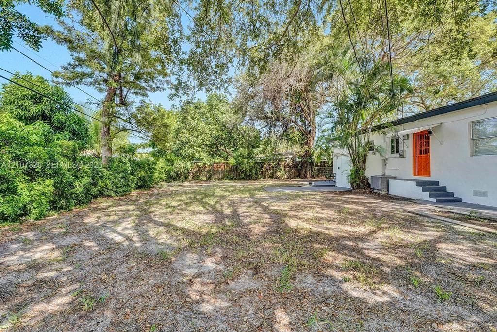 Expansive backyard featuring mature trees, established landscaping, and a concrete patio