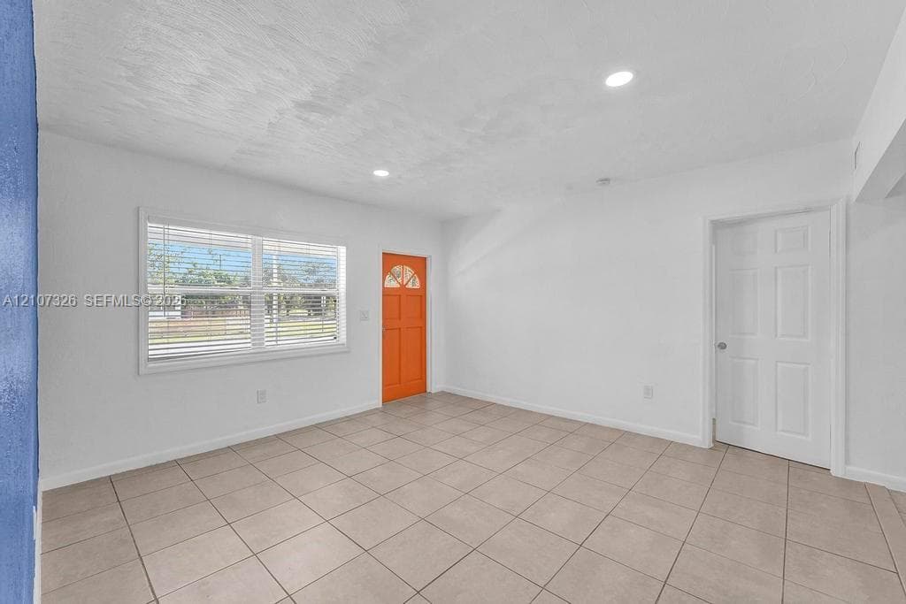 Interior space featuring neutral tile flooring, recessed lighting, a multi-pane entry door, and a horizontal window with adjustable blinds