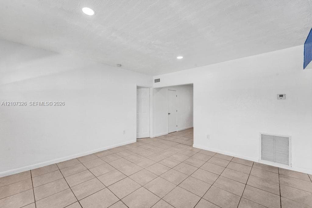 Neutral-toned tile flooring, recessed ceiling lighting, and crisp white wall finishes