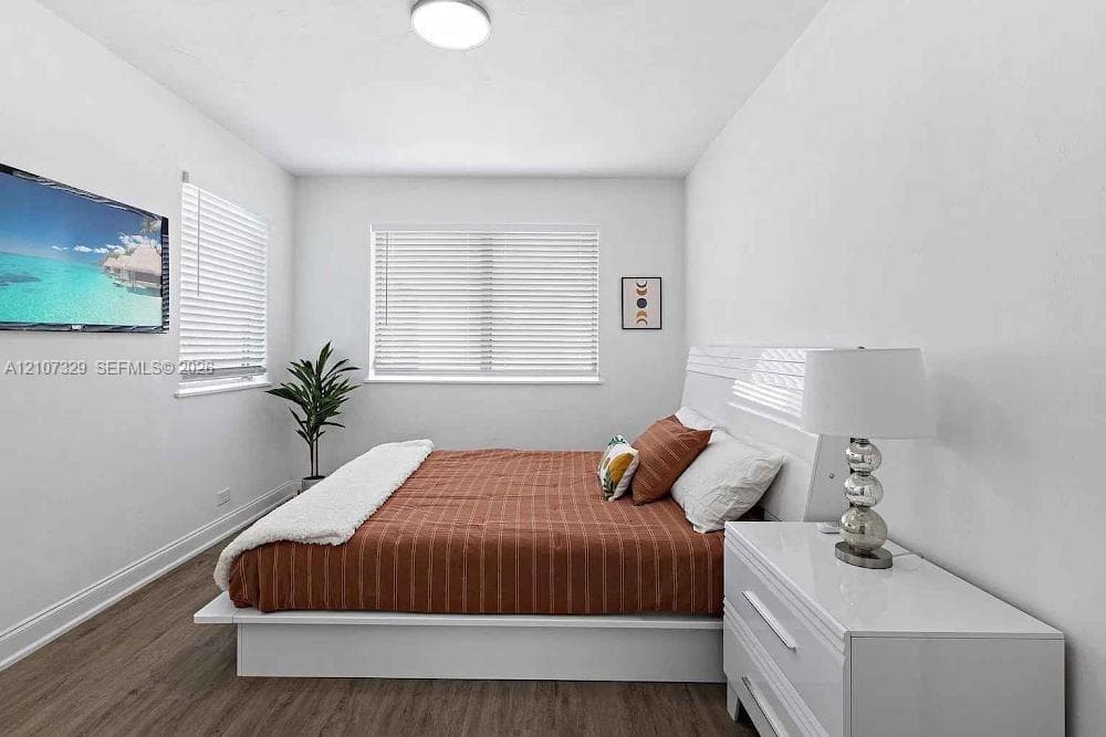 Bedroom with bed, nightstands, and wood-look flooring.