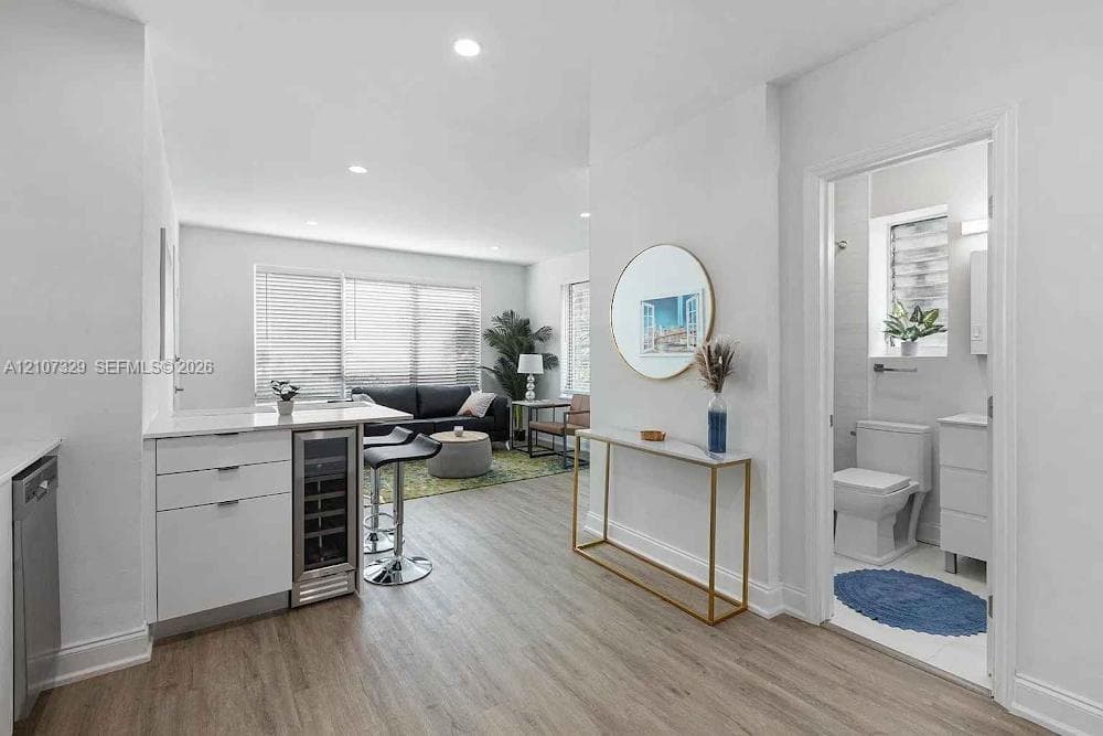 Kitchen featuring a white peninsula with an integrated beverage cooler, recessed lighting, and wood-finish flooring throughout