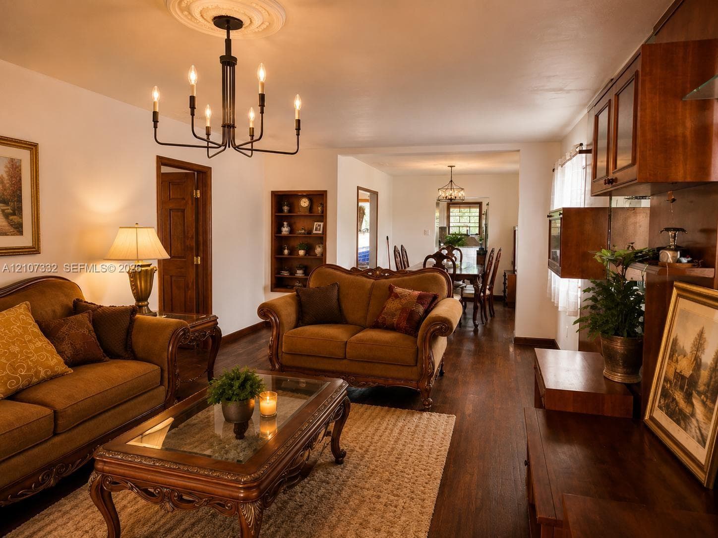 Living area featuring wood-finish flooring, a decorative ceiling medallion, an exposed built-in display niche, and dark-toned built-in cabinetry