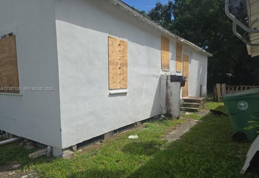 Exterior elevation featuring white stucco siding, concrete stairs, and wooden window coverings