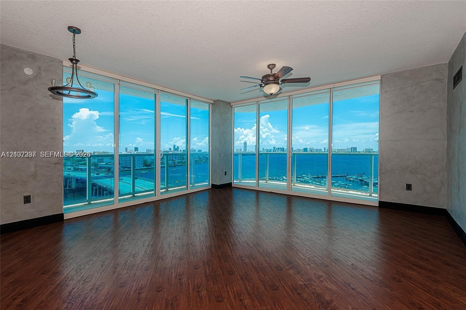 Floor-to-ceiling windows, wood-finish flooring, textured wall treatments, ceiling-mounted light fixture, and integrated ceiling fan