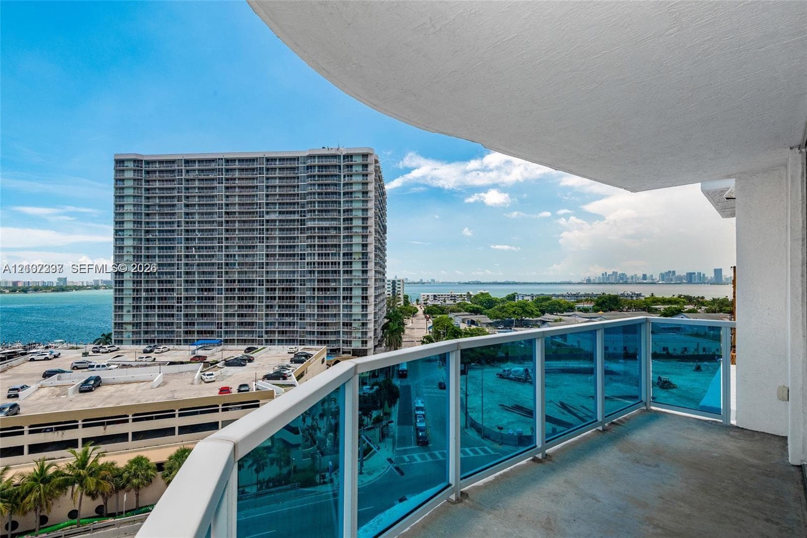 Covered balcony featuring blue-tinted glass railings and concrete flooring